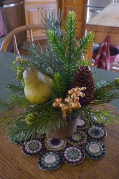 a table topped with a vase filled with pine cones and other decorations on top of it