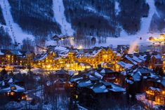 an aerial view of a ski resort at night with snow on the ground and lit up buildings