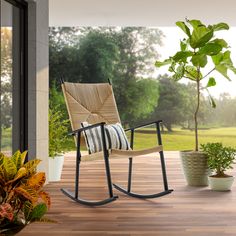 a rocking chair sitting on top of a wooden deck next to a potted plant