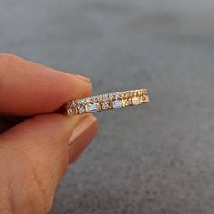 a hand holding a gold and diamond ring