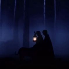 two people standing in the dark with a lantern