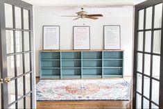 an open door leading to a living room with blue bookshelves and pictures on the wall