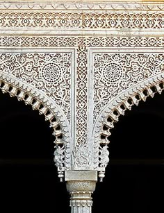 an intricately designed white building with arches and pillars in the center is seen against a black background