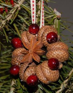 a pine cone ornament hanging from a tree with red berries and cones on it