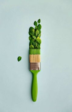 a toothbrush with green leaves on it sitting on top of a blue surface next to another brush