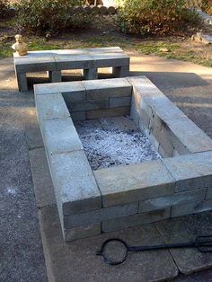 an outdoor fire pit with two benches in the background