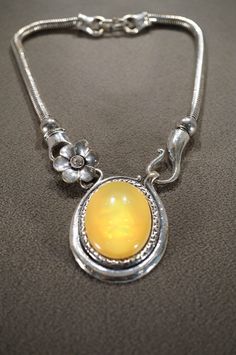 I am offering this very unique vintage silver tone pendant style necklace. This piece is featuring an oval yellow single stone set in a silver etched bezel setting on a slinky style chain with a small flower detail at the stone. This necklace is measuring app 15 inches in length. Please be sure to view all of my photos as they are a very important part of my listing. Collectible Oval Amber Necklaces, Vintage Oval Necklace With Polished Finish, Vintage Oval Necklaces With Polished Finish, Vintage Gemstone Necklace With Oval Cabochon, Vintage Hallmarked Oval Cabochon Necklace, Vintage Oval Sterling Silver Necklaces, Vintage Oval Gemstone Necklace, Vintage Yellow Jewelry With Cabochon, Vintage Yellow Cabochon Jewelry