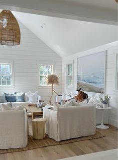 a woman sitting on a couch in a living room with white walls and wood floors