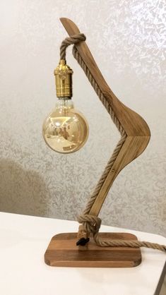 a lamp made out of wood and rope with a light bulb on top of it