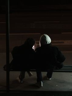 two people sitting on a bench at night