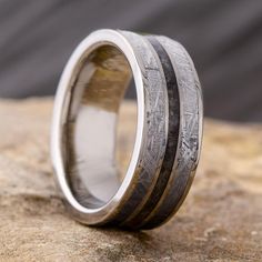 This mens meteorite wedding band has a dark inlay of crushed onyx between the gibeon meteorite. A titanium and meteorite ring is perfect for celebrating your vows.Astronomy jewelry attests to the magnificence that exists in our universe. This meteorite ring shows a fantastic Widmansttten pattern. It has been etched with an acid to reveal the characteristic patterns, or Widmansttten figures, of iron meteorites. No two etched meteorites will have the exact same pattern, making your wedding band a Men’s Wedding Bands Meteorite, Onyx Wedding Band Men, Man Wedding Ring Silver, Meteorite Wedding Band Mens, Men’s Wedding Band, Mens Engagement Rings Silver, Cool Mens Wedding Bands, Mens Engagement Rings, Mens Silver Wedding Bands