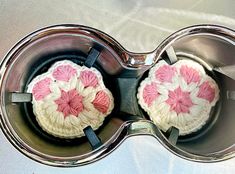 two crocheted pink and white flowers in a silver bowl