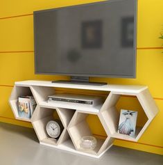 an entertainment center with shelves and a flat screen tv on the wall in front of a yellow striped wall