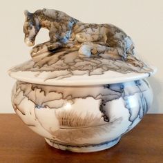 a white and black bowl with a horse figurine on it's lid