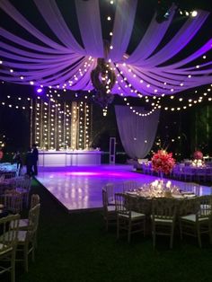 an outdoor dance with purple lighting and white drapes over the dance floor at night