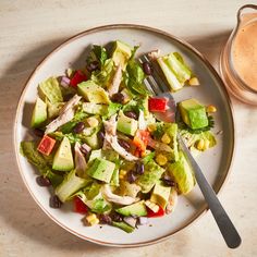 a white plate topped with a salad next to a cup of coffee and a spoon