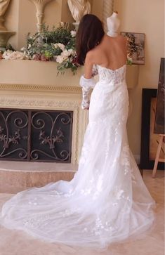 a woman in a wedding dress looking at the fireplace