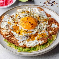 an egg and avocado toast on a white plate