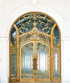 an ornate gold door with glass panels and wrought iron work on the front entrance to a building