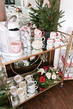 a christmas display with coffee mugs, cups and other items on a gold shelf