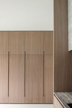 an empty kitchen with wooden cabinets and marble counter tops in front of a white wall