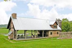 a rustic log cabin sits in the middle of a grassy field with a picnic table