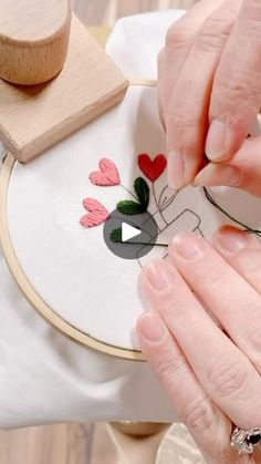 a woman is working on a embroidery project with her hands and needle in the hoop