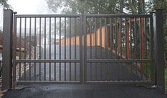 a gated entrance to a road with trees in the background