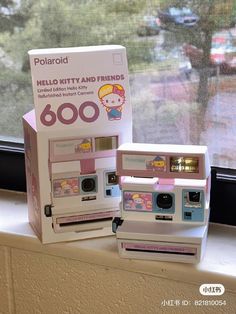 two polaroid cameras sitting on top of a window sill next to a box