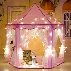 a teddy bear sitting in a pink tent with fairy lights