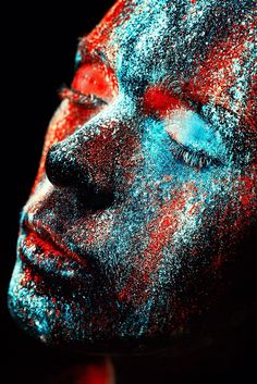 a woman's face covered in blue and red powder