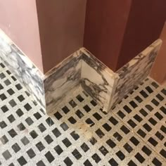 the corner of a bathroom with black and white tiles on the floor next to it