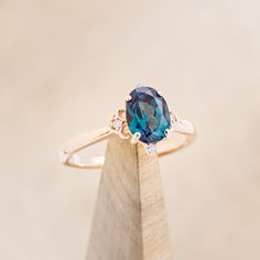 a blue diamond ring sitting on top of a wooden stand