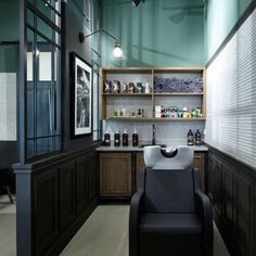 a room that has a chair in it and shelves with bottles on the wall next to it