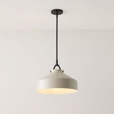 a white light hanging from the ceiling in a room with gray walls and flooring