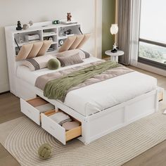 a white bed with drawers underneath it in a living room next to a large window