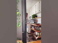 an open door leading to a kitchen with white cabinets and wood flooring on the walls