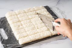 someone using a knife to cut up some food on a sheet of tin foil with a spatula