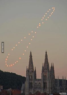 an airplane flying in the sky over a church with lights on it's side