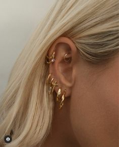 a woman with blonde hair wearing gold ear cuffs and piercings on her left ear