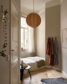 a bedroom with a bed and some clothes hanging on the wall next to a window