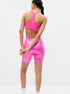 a woman in pink sports bra top and shorts standing back to back with her hands on her hips