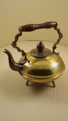 an antique tea kettle with a wooden handle