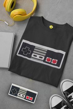 a t - shirt with a video game controller on it next to headphones and other items