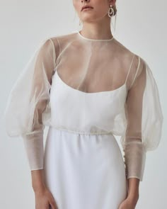 a woman wearing a white dress with sheer sleeves