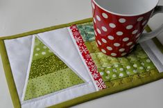 a coffee cup sitting on top of a table next to a piece of quilted material