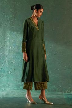 Deep green chanderi kurta with metallic stripe pattern panels on collar and sleeve borders. Paired with stripe pattern palazzo and dupatta. Components: 3 Pattern: Woven Type Of Work: Stripe Pattern Neckline: V Collar Sleeve Type: Full Sleeves Fabric: Kurta and Dupatta: Chanderi, Palazzo and Lining: Cotton Color: Green Other Details:  Stripe pattern dupatta border Side slits on kurta Attached lining Length: Kurta: 44 inches Palazzo: 35 inches Dupatta L x W: 90 x 30 inches Note: Potli shown in the Aline Suits Design, Kurta With Dupatta For Women, Aline Kurta Designs, A Line Kurta Designs, Straight Kurta Designs, Striped Kurti Design, Chanderi Kurta Designs, A Line Kurti Designs, Straight Kurti Designs