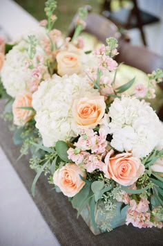 an arrangement of white and peach flowers on a table