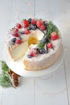 a white cake with berries and pine on top