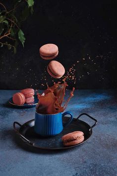 macaroons falling into a blue cup on a black plate with sprinkles